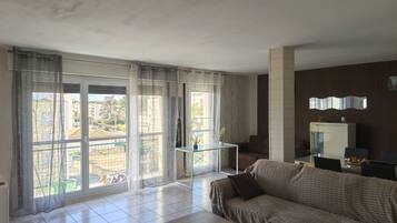 A living room with a sofa, a coffee table, and a view through large windows.