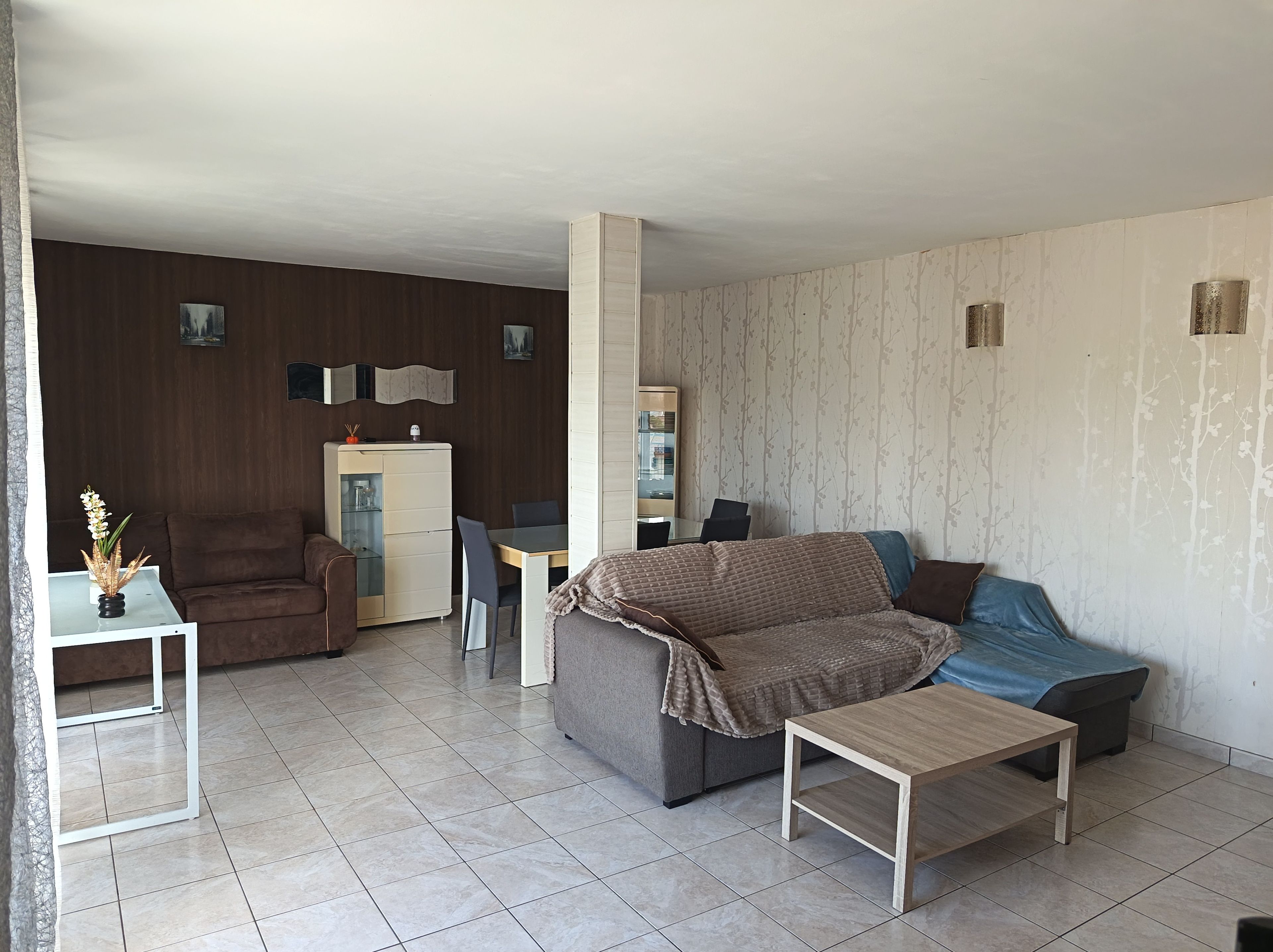 A living room with a sofa, a coffee table, a dining table, and a cabinet.