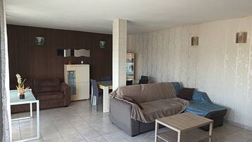 A living room with a sofa, a coffee table, a dining table, and a cabinet.