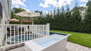 A swimming pool with a deck, a pergola with umbrellas, and a well-maintained hedge. - Beautifully updated East Hampton retreat with a heated pool, sauna, and... (East Hampton)