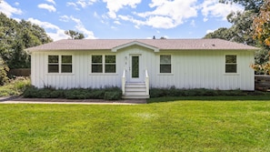 A single-story house with a front porch, a small front yard, and a clear sky. - Beautifully updated East Hampton retreat with a heated pool, sauna, and... (East Hampton)