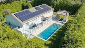 A modern house with a swimming pool, solar panels, and a deck. - Beautifully updated East Hampton retreat with a heated pool, sauna, and... (East Hampton)