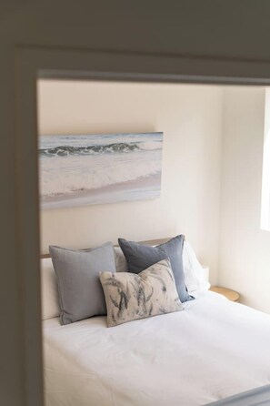 A bedroom with a bed, pillows, and a wall-mounted artwork. - Manly 2BR | 5 Min Walk to Beach + Parking (Manly)