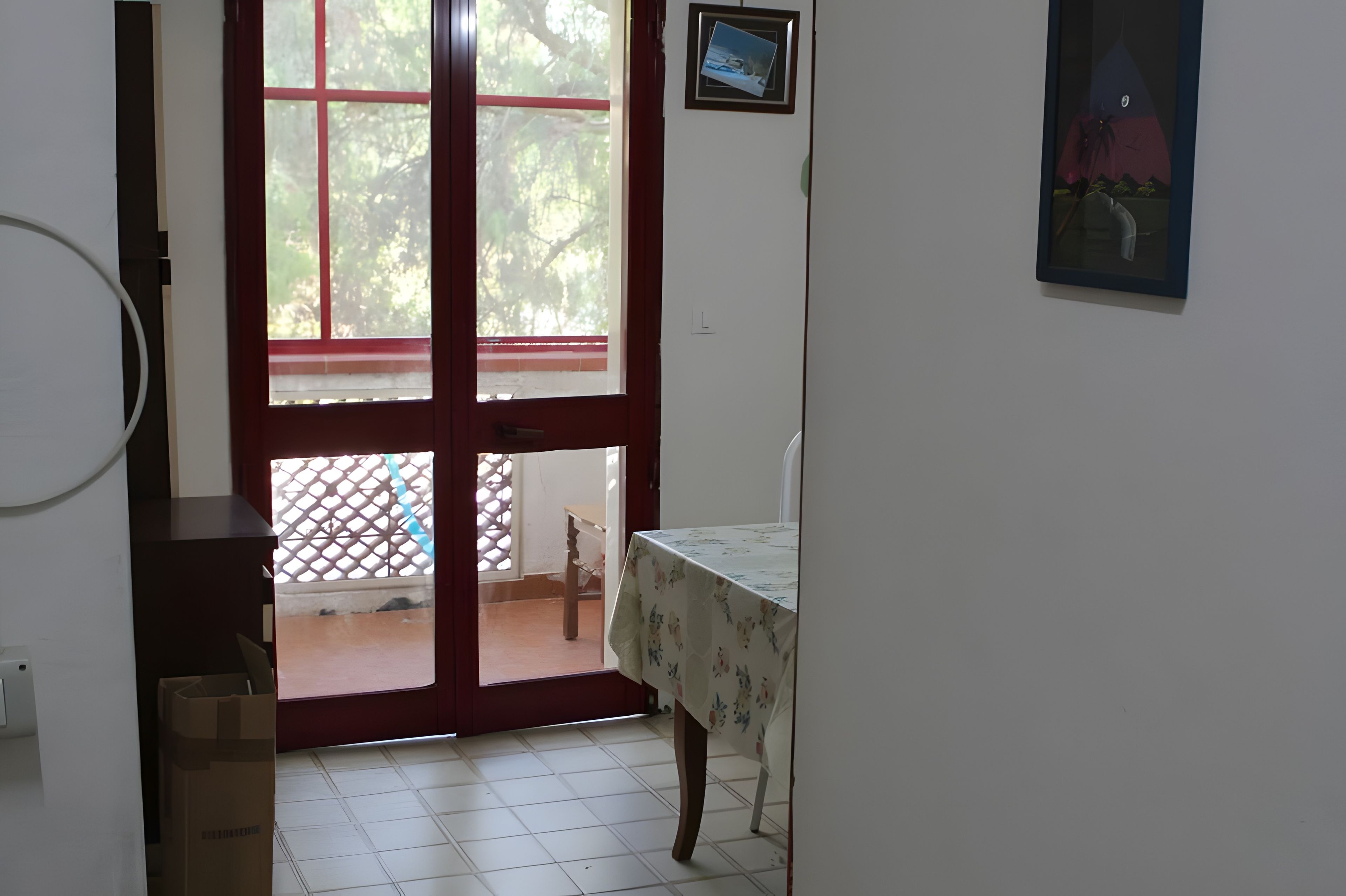 A room with a sliding glass door leading to an outdoor area with a wooden table and chairs.