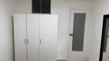 A room with a large wardrobe, a door with a frosted glass panel, and a window above the wardrobe.