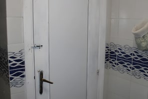 A bathroom with a white door, a towel rack, and patterned tiles.