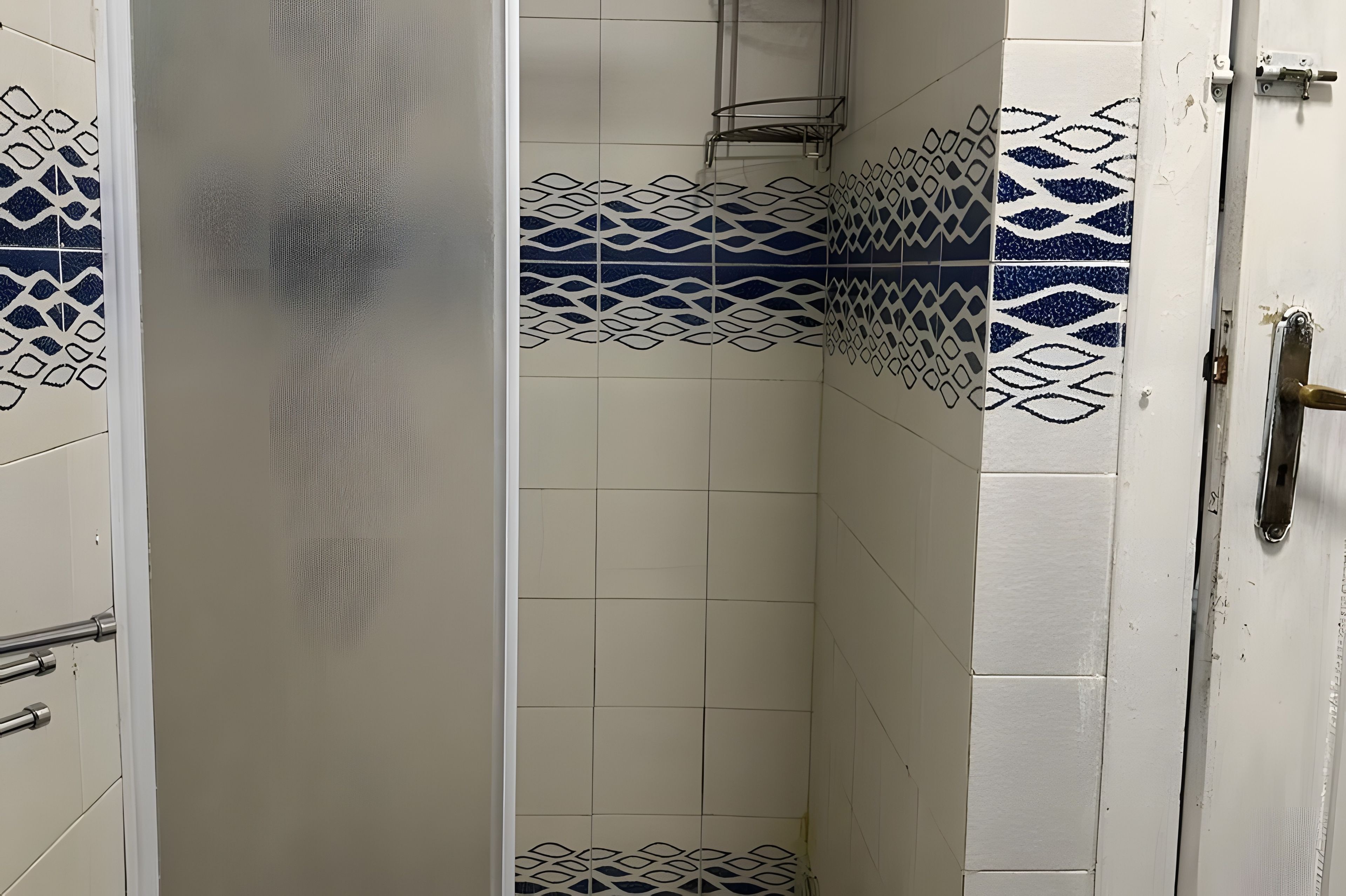 Ein Badezimmer mit weißen Fliesen und blauen Dekormustern.