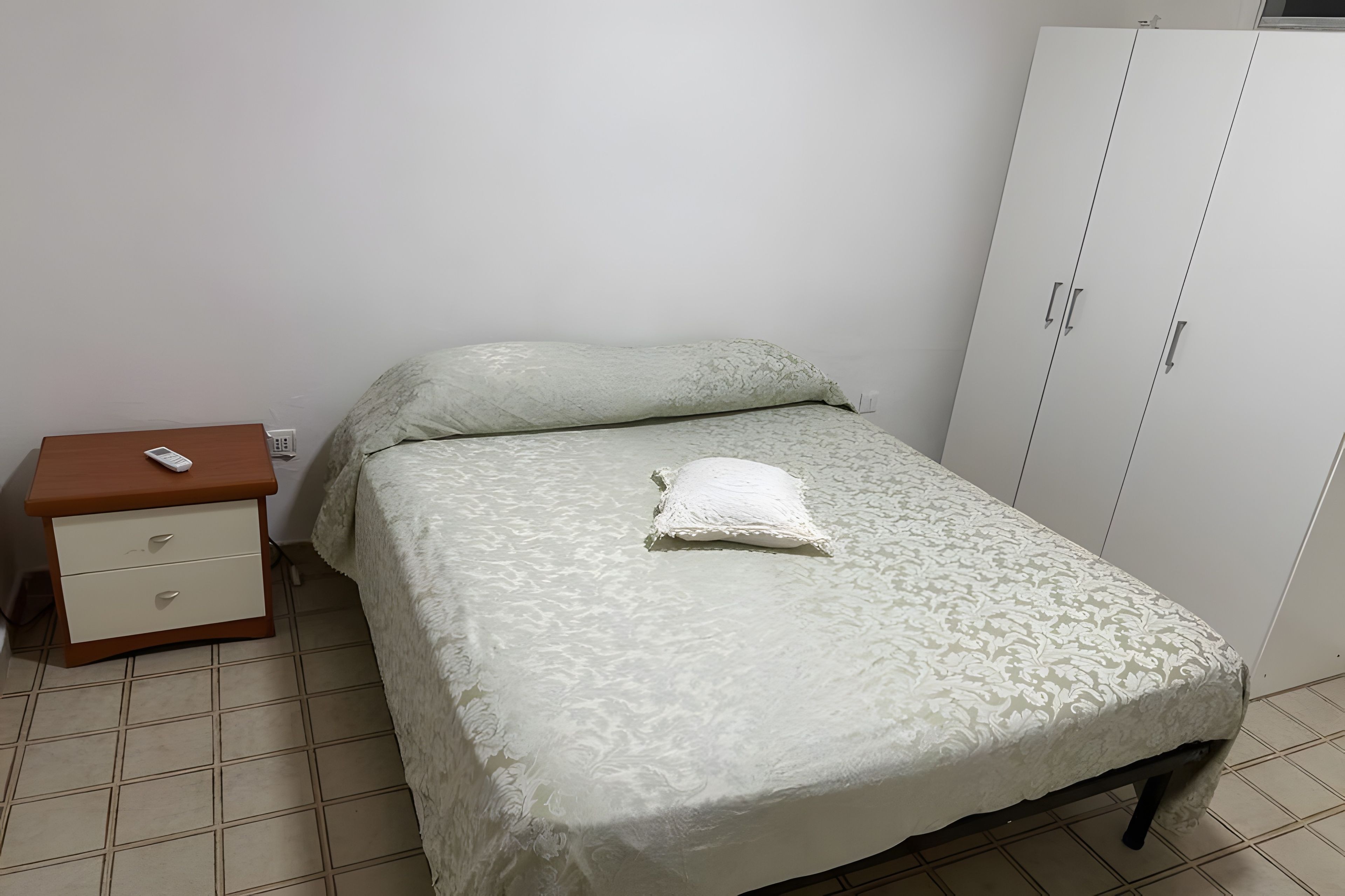 A bedroom with a bed, a nightstand, and a wardrobe.