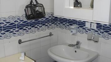 A bathroom with a white sink, a towel rack, a mirror, and a patterned tile backsplash.