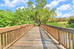 Eine Holzbrücke mit Geländern, umgeben von üppiger Vegetation und Bäumen.