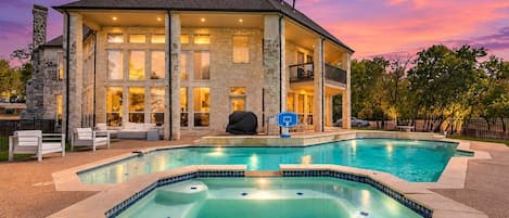 A two-story house with a swimming pool, stone exterior, and a covered patio area.