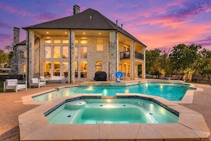 Ein zweistöckiges Haus mit Swimmingpool, Steinaußenwand und überdachter Terrasse.