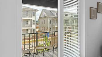A room with a sliding glass door leading to a balcony with a metal railing and a small table.