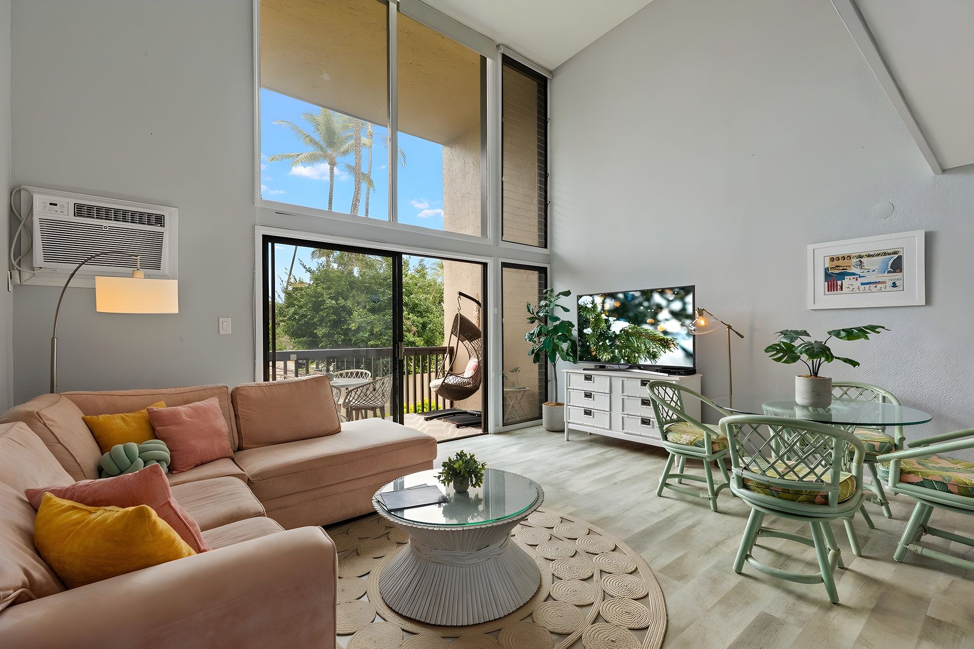 A spacious living area with a large window, a sofa, a coffee table, and a dining set.