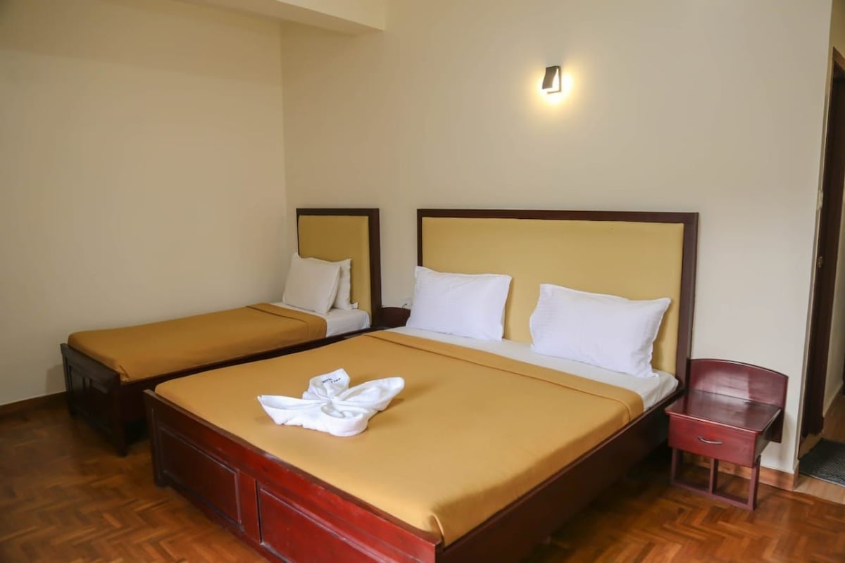 Una habitación de hotel con dos camas individuales, una mesita de noche de madera y una pequeña mesa.