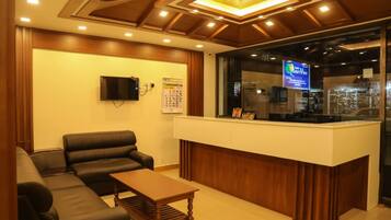 A reception area with a reception desk, a flat-screen TV, a sofa, and a coffee table.