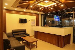 Una zona de recepción con mostrador, televisor de pantalla plana, sofá y mesa de centro.