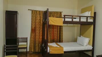A bunk bed with a wooden frame, a single chair with a cushion, and a curtain with a patterned design.