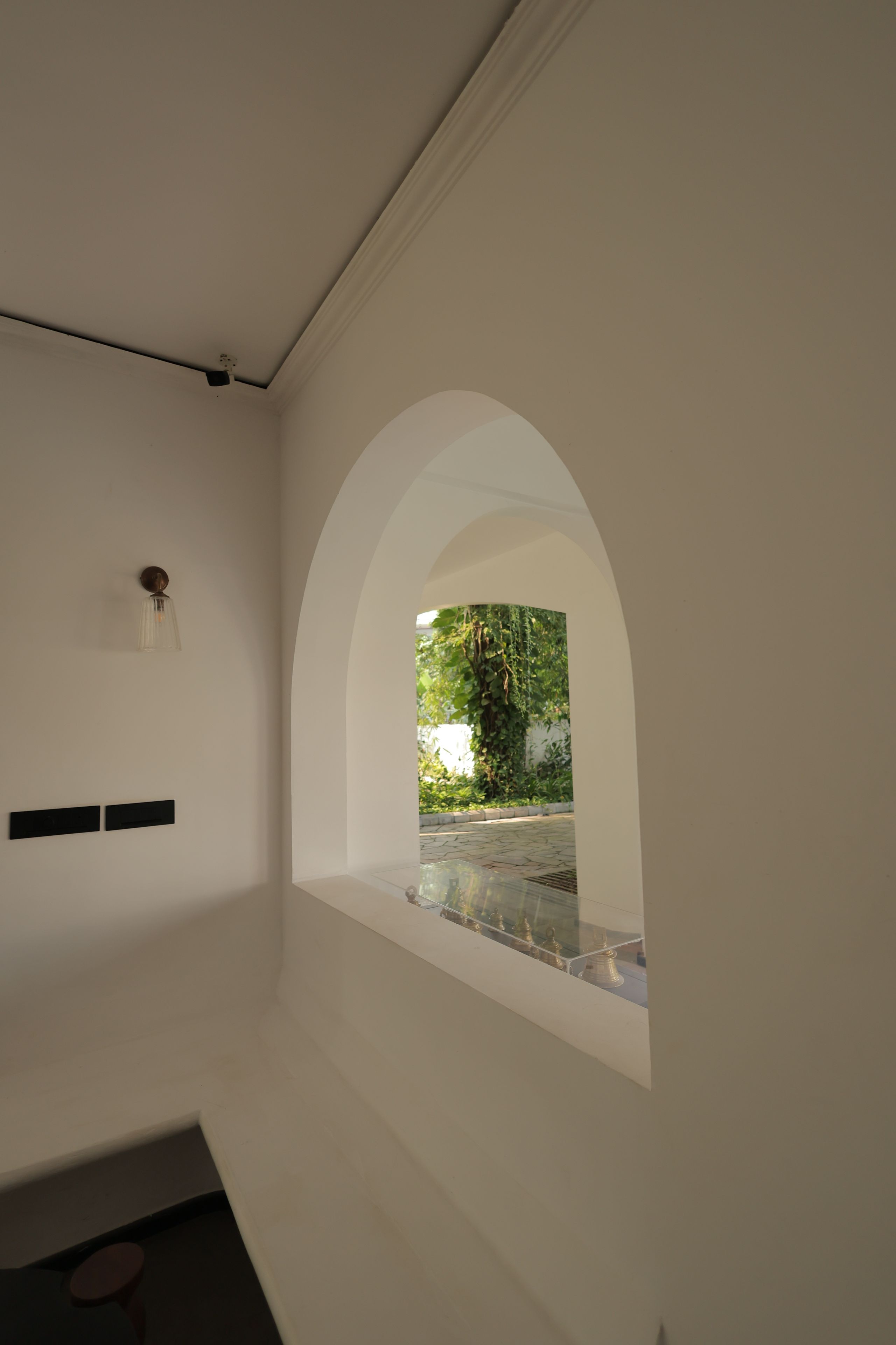Un interior minimalista con un ventanal que da a un jardín exterior.