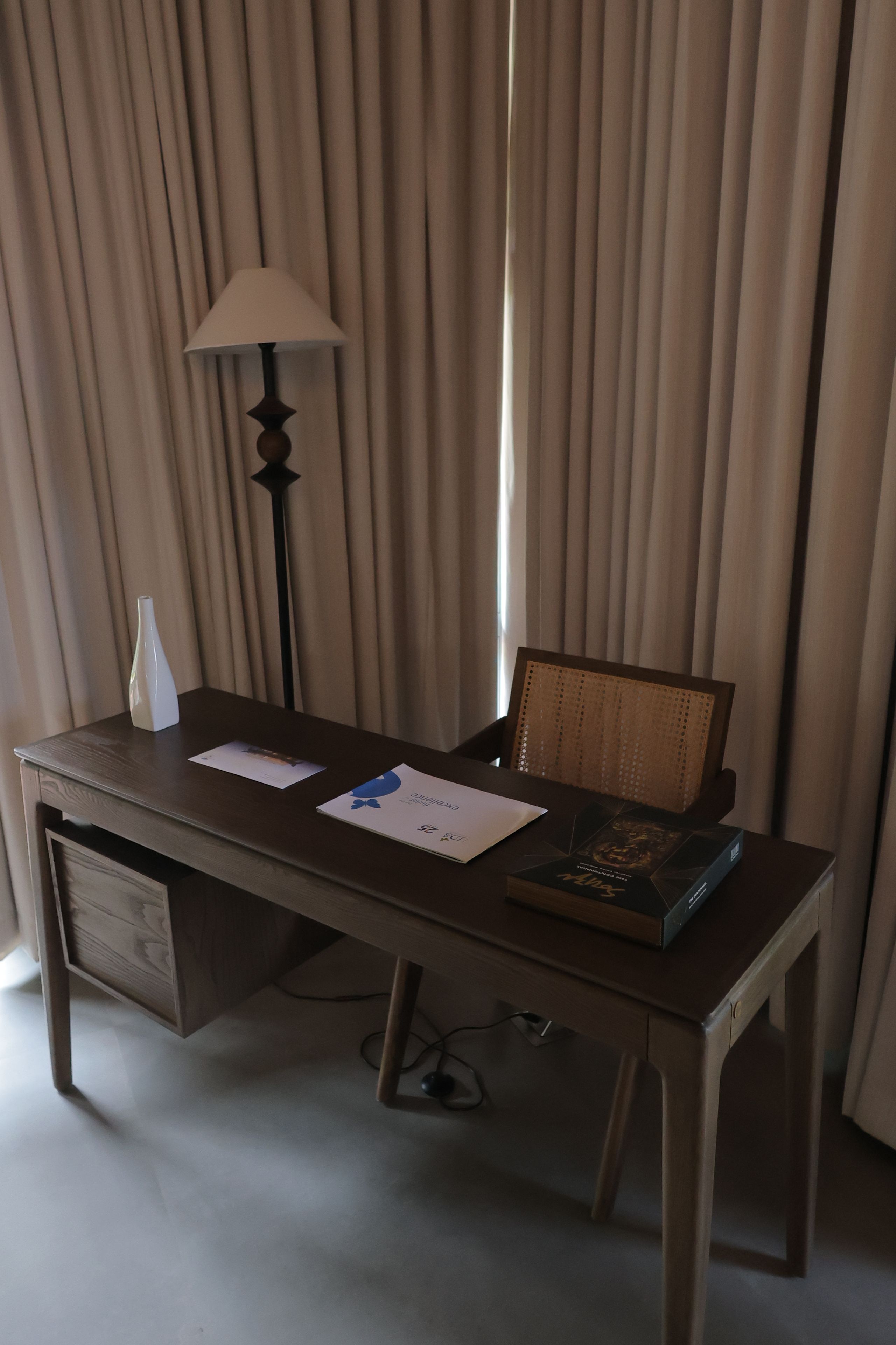 Una habitación de hotel con un escritorio de madera, una lámpara, una silla y una cama.