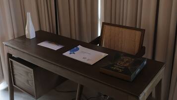 Una habitación de hotel con un escritorio de madera, una lámpara, una silla y una cama.