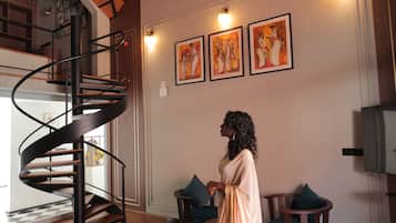 Una habitación amplia con una escalera en espiral, piso de madera y obras de arte en las paredes.
