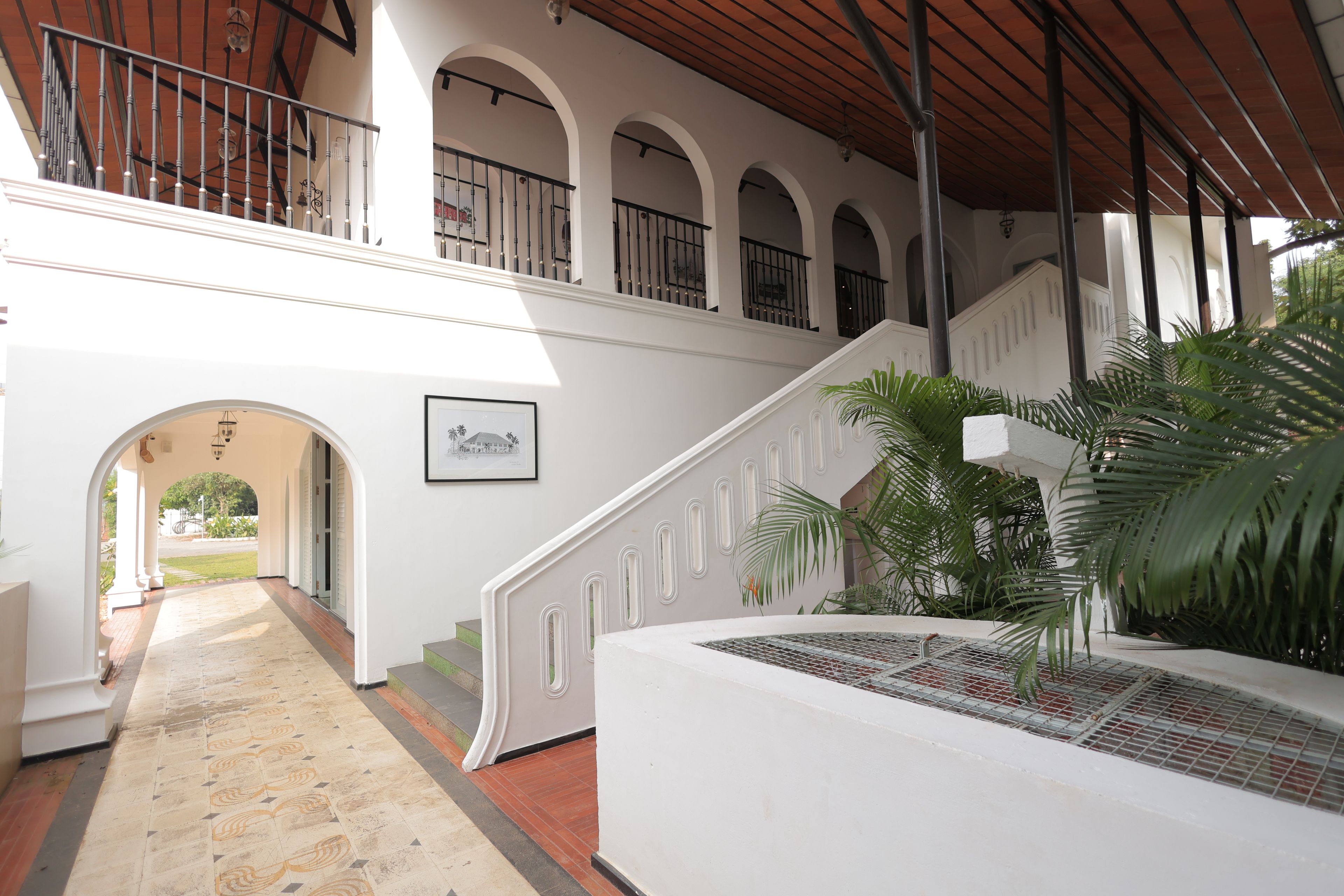 Un espacio al aire libre cubierto con una escalera que lleva a un nivel superior, piso de baldosas y un cuadro en la pared.