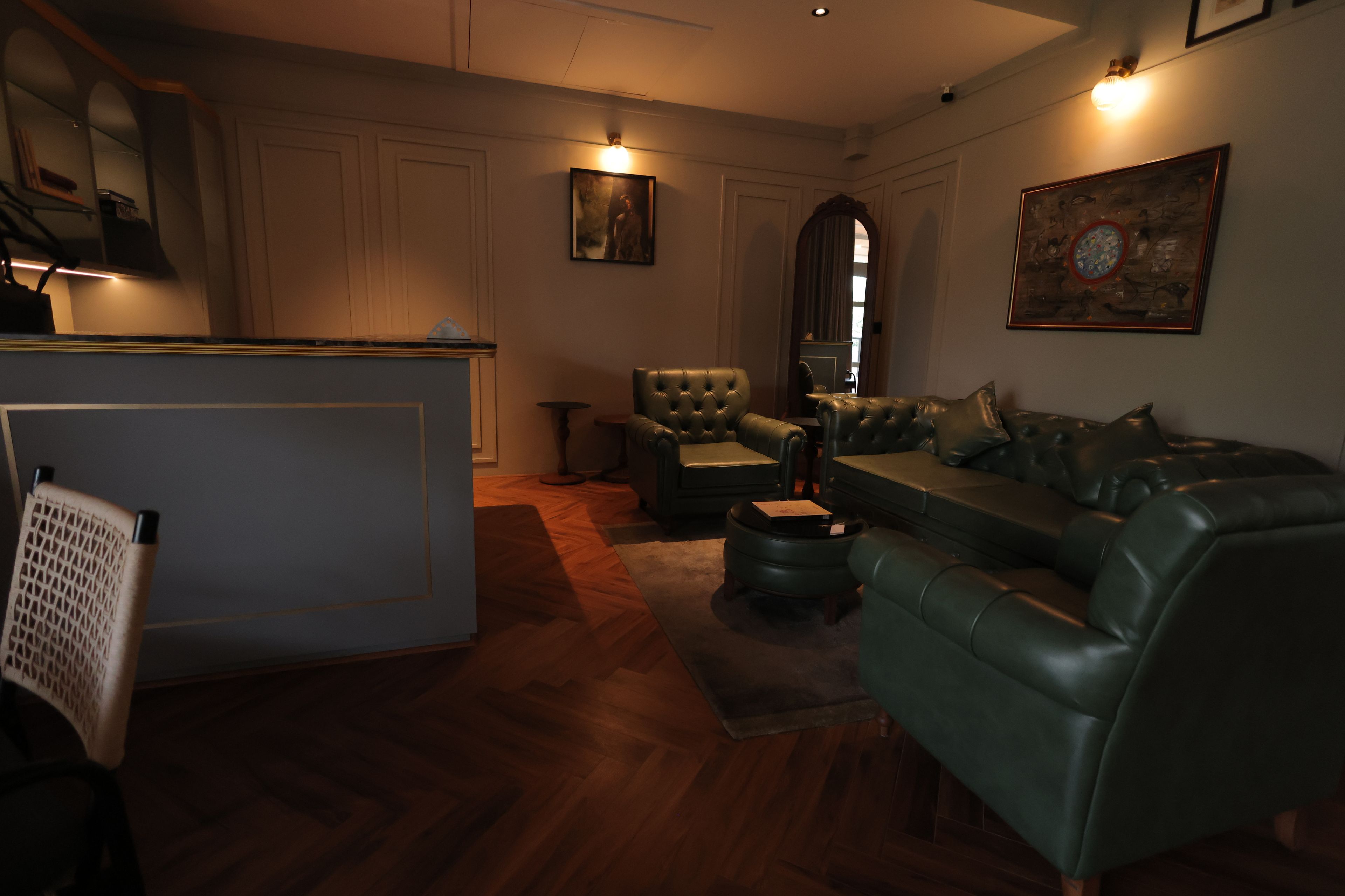 A living room with a sofa, a chair, a small table, and a decorative mirror.