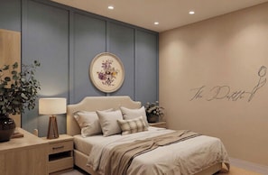 Un dormitorio con cama, mesitas de noche, lámpara, planta en maceta y un cuadro floral con la firma del artista.
