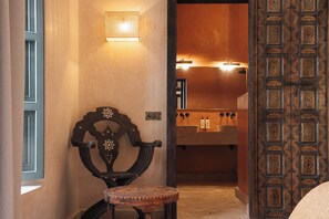 A traditional interior with a wooden chair, a small round table, and a door with intricate patterns. - Fabulous 4-bedroom Riad with Pool in vibrant Marrakech (Marrakech)