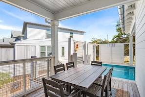 A covered patio with a pool, a dining table, and chairs. - Sunkissed & Salty (Panama City Beach)