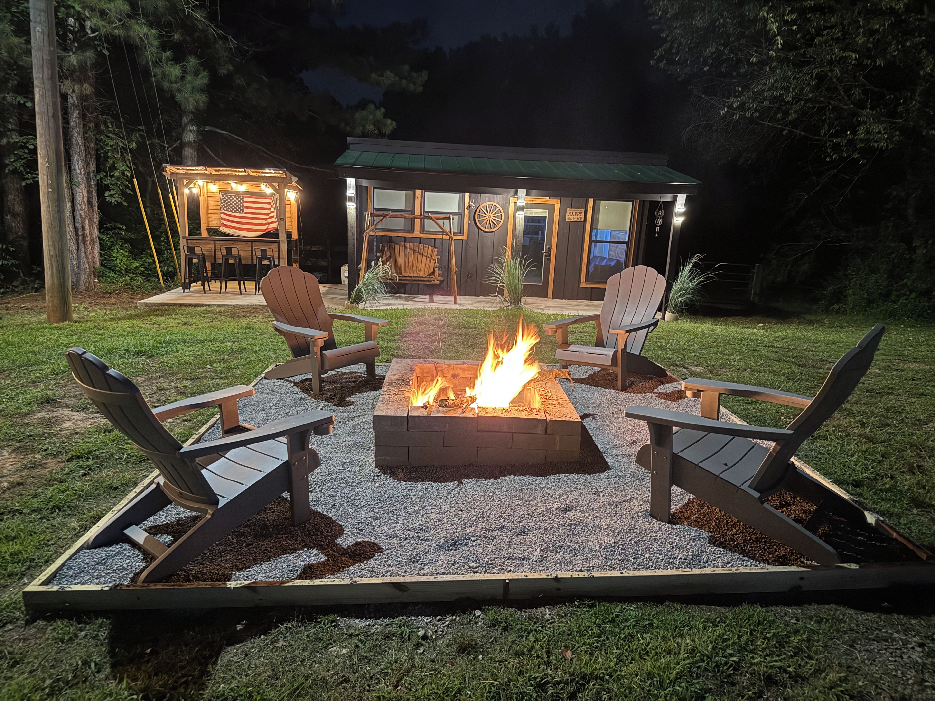 An outdoor seating area with a fire pit and Adirondack chairs.
