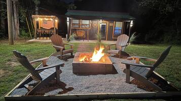 An outdoor seating area with a fire pit and Adirondack chairs.