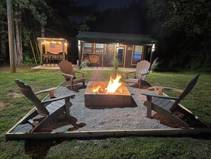 An outdoor seating area with a fire pit and Adirondack chairs.