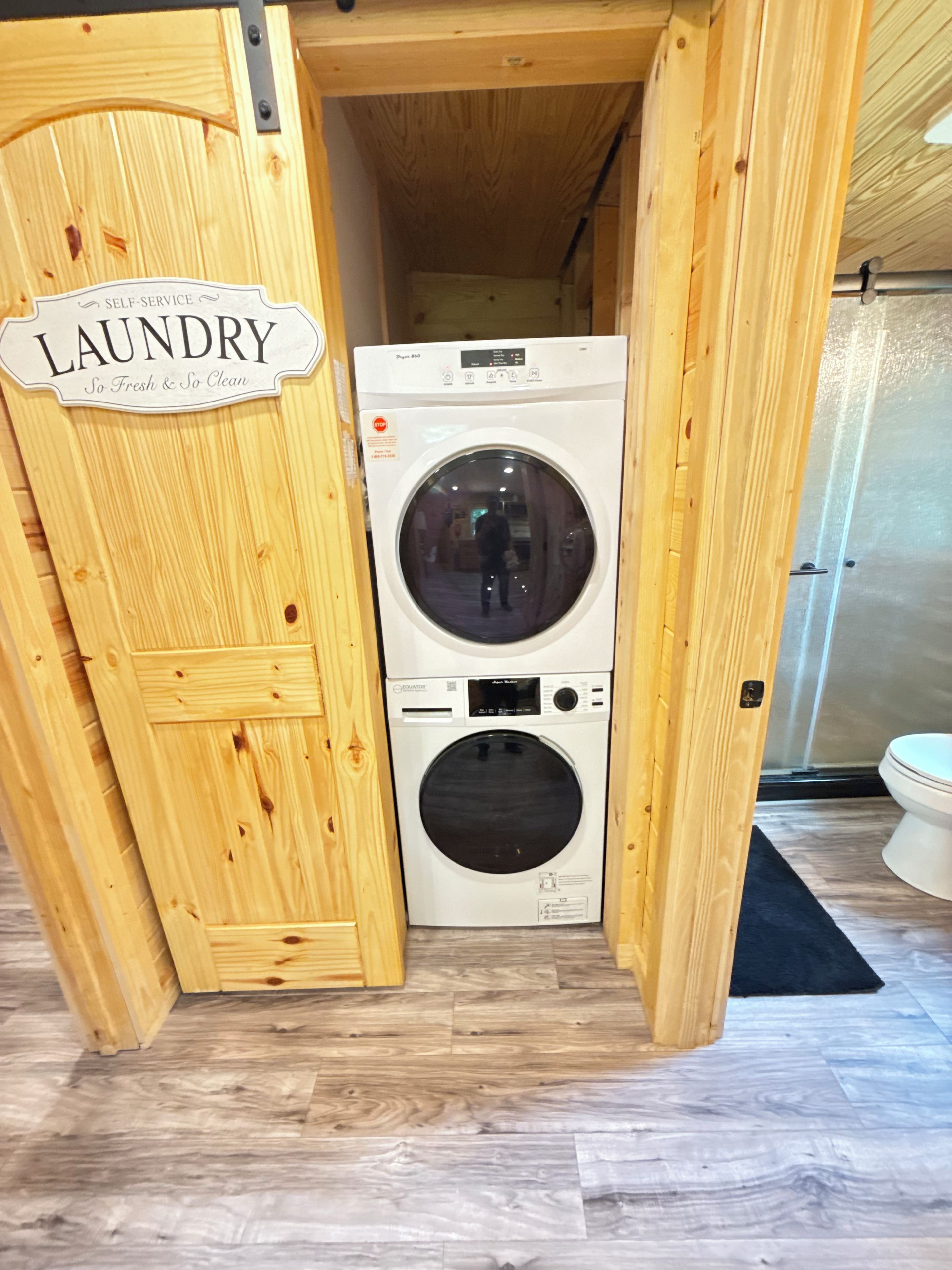 A laundry room with a wooden door labeled 'LAUNDRY' and a front-loading washing machine.