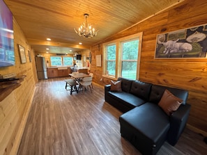 A wooden interior with a dining area, kitchen, and a large window.