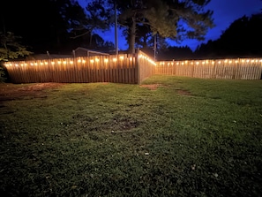 A fenced yard with a wooden fence and string lights. - The little cabin retreat (Bowdon)