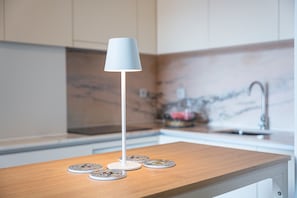 A modern kitchen with a white lamp on a wooden countertop, a marble backsplash, and a stainless steel faucet. - GuestReady - Cozy Porto Retreat with Balcony (Porto)