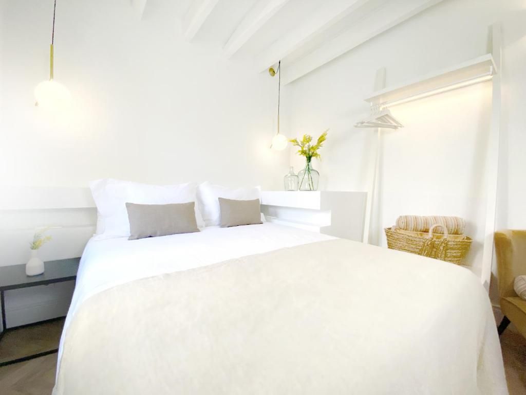 Una habitació d'hotel amb un llit gran, taules de nit, una làmpada, un vas amb flors i una cadira.