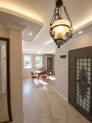 A spacious dining area with a chandelier, a kitchen in the background, and a decorative door. - Luxury 4-Bedroom Villa with Private Saltwater Pool in Dalyan (Muğla)
