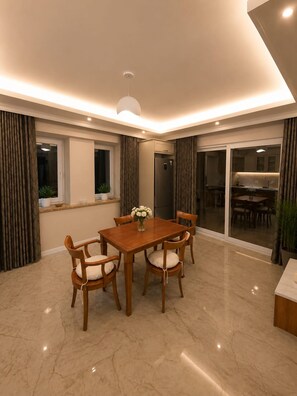 A dining area with a wooden table and chairs, a vase of flowers, and a modern ceiling light. - Luxury 4-Bedroom Villa with Private Saltwater Pool in Dalyan (Muğla)