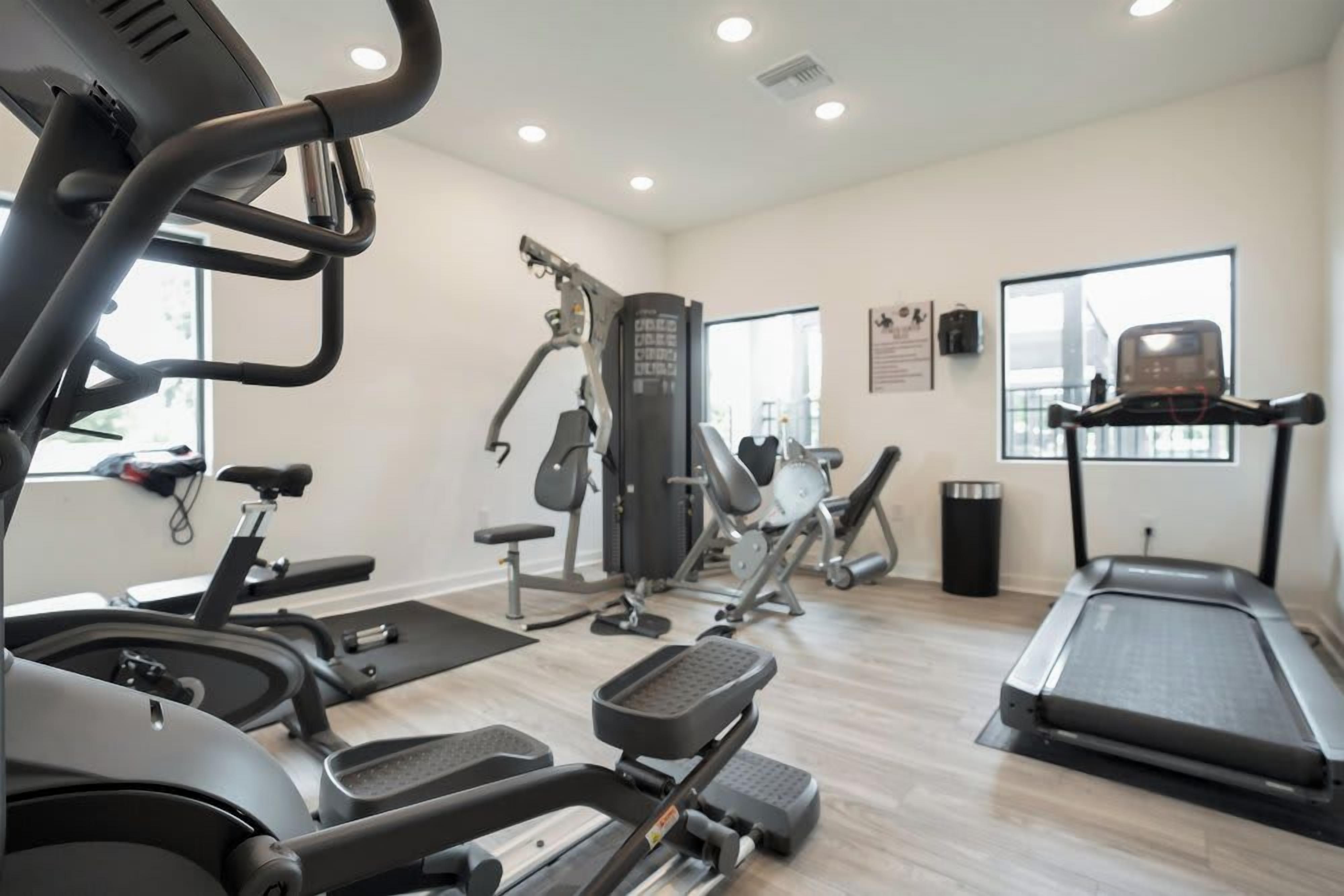 Une salle de sport équipée de machines de cardio, d’appareils de musculation et d’un tapis de course.