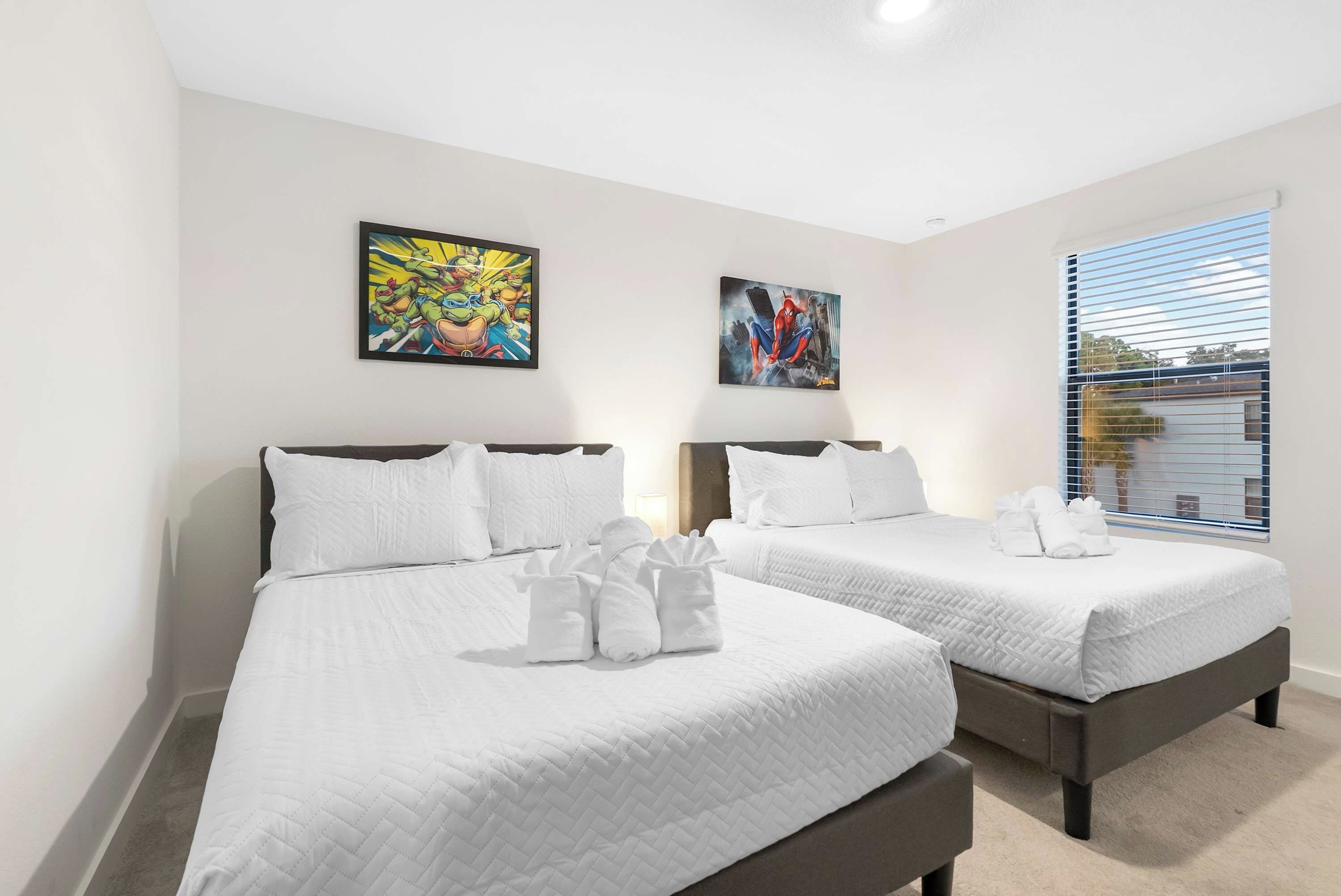 A hotel room with two beds, white bedding, and artwork on the walls.