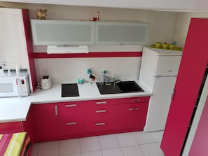 A kitchen with white cabinets, a red countertop, a microwave, a toaster, and a sink. - House in a complex with a swimming pool in the summer, 900 meters from the beach (Batz-sur-Mer)