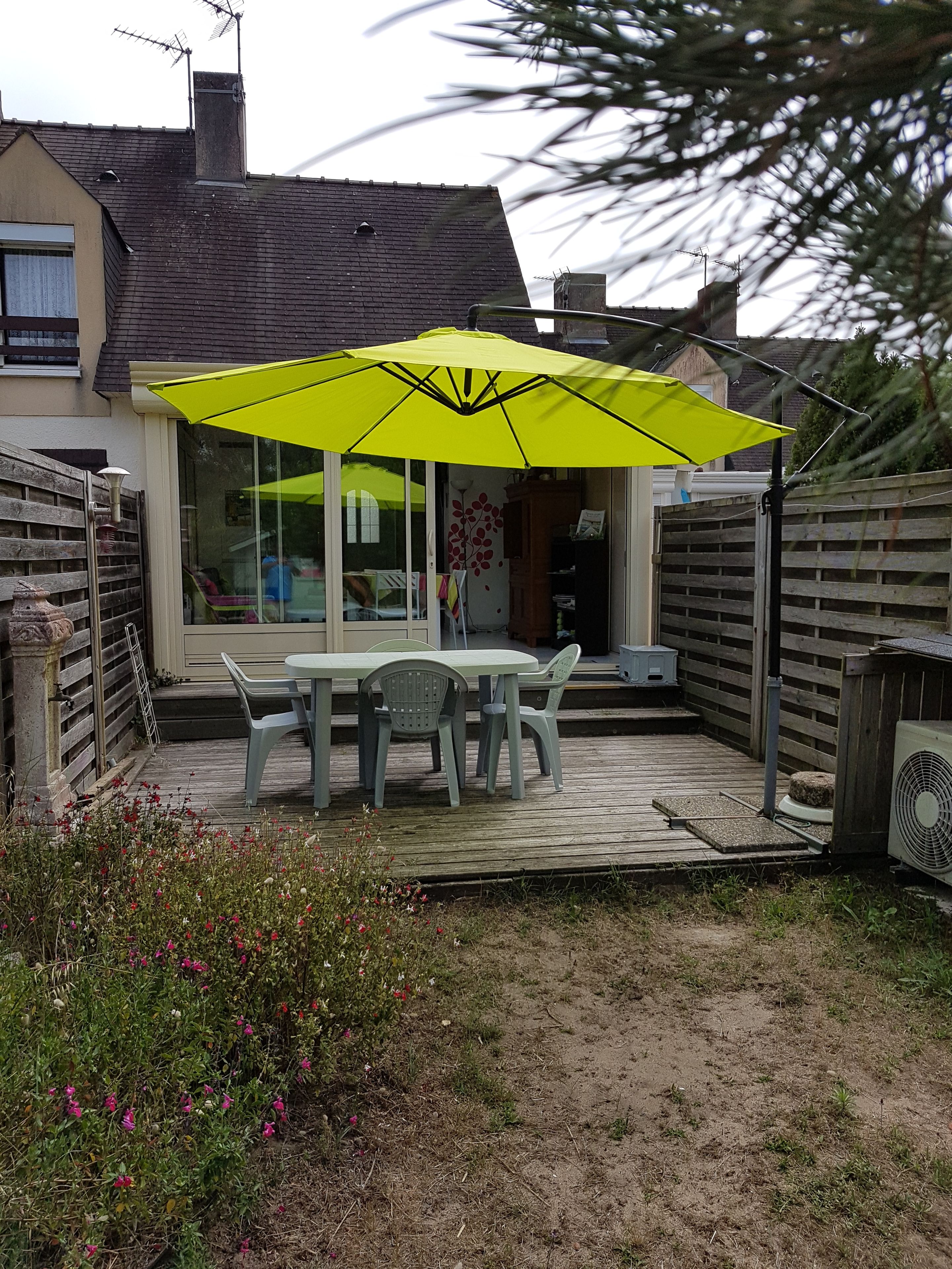 A patio with a table and chairs, a yellow umbrella, and a wooden deck.
