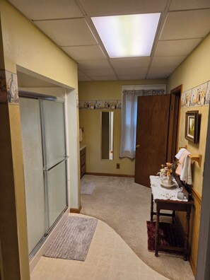 A bathroom with a shower, a vanity with a mirror, and a towel rack.