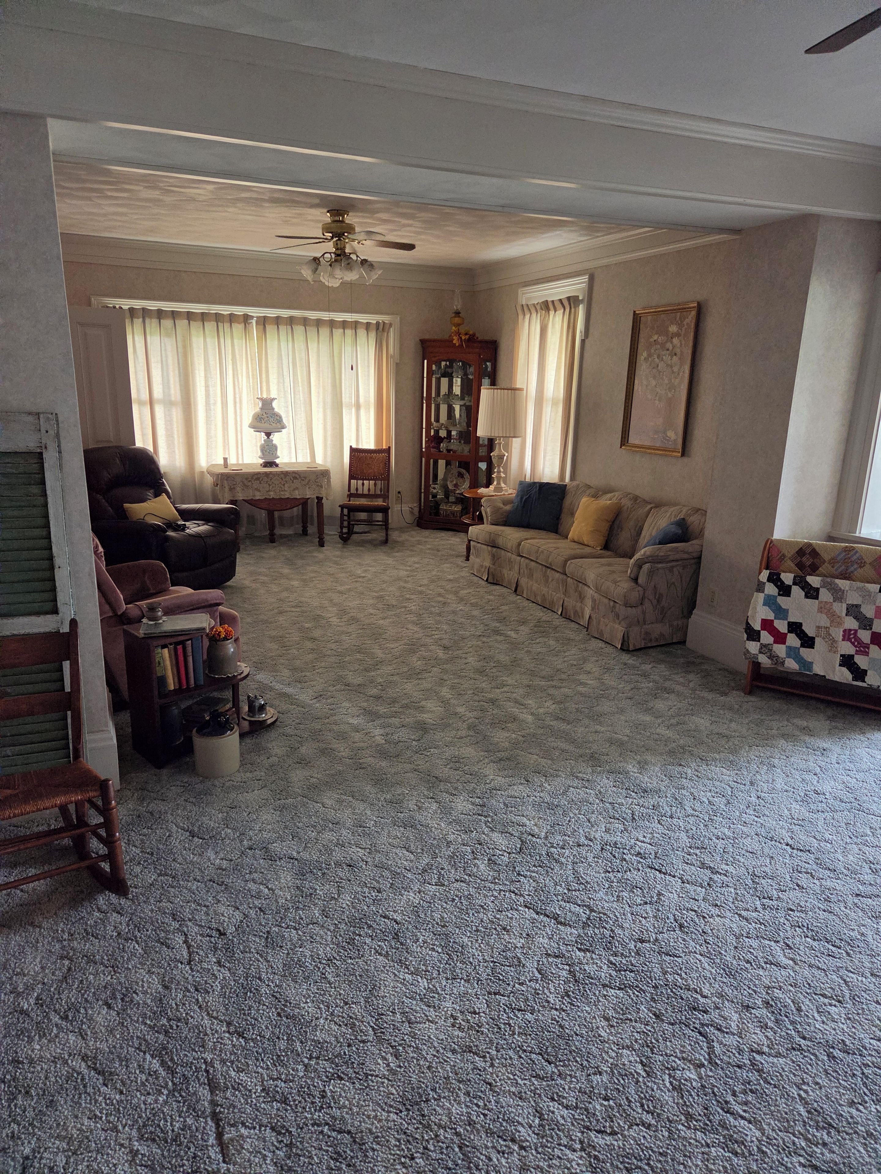 A living room with a ceiling fan, a fireplace, a sofa, a chair, and a bookshelf.