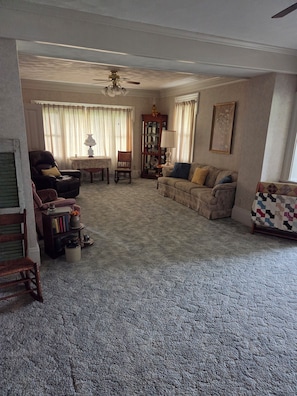 A living room with a ceiling fan, a fireplace, a sofa, a chair, and a bookshelf.