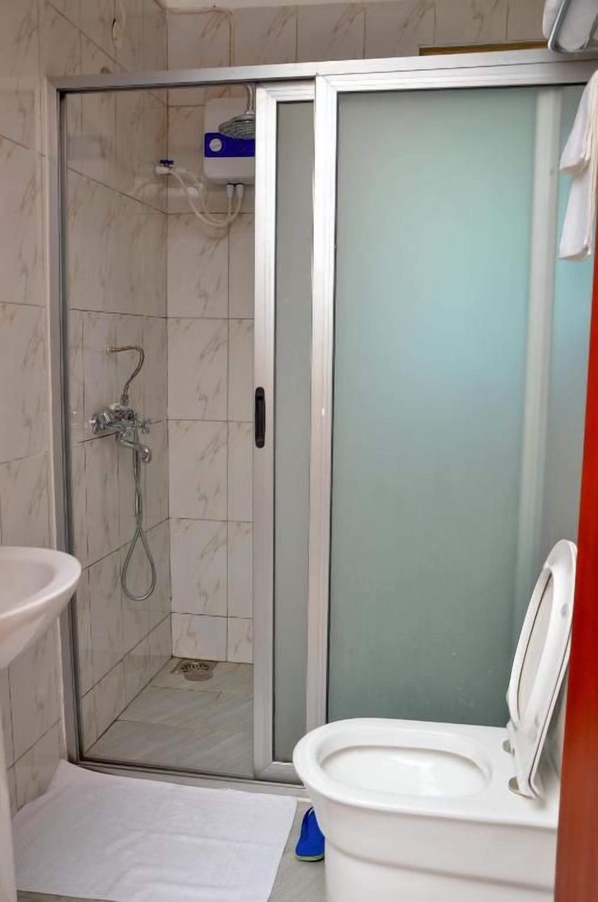 Un baño con ducha envuelta en vidrio, un inodoro y un lavamanos.
