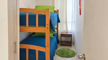 A small, well-lit room with a bunk bed, a bedside table, and a green rug.
